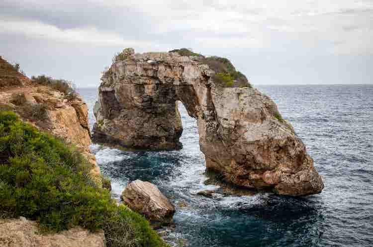 rocks-in-the-ocean-next-to-trees-and-mountains
