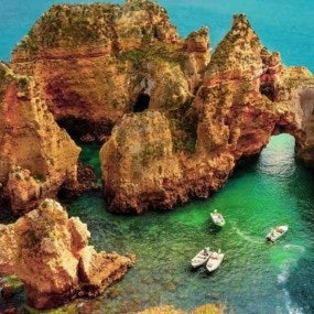 Seascape featuring a group of boats resting in the calm waters of rocky cliffs
