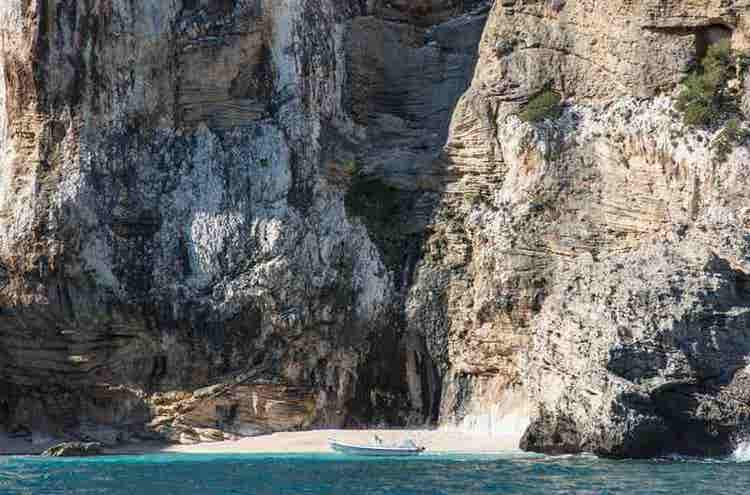 a-small-boat-approaching-a-majestic-cliffside-beac